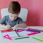 Enfant concentré, crayon en main, coloriant une page thématique d'Halloween avec des citrouilles, des fantômes et une maison hantée.