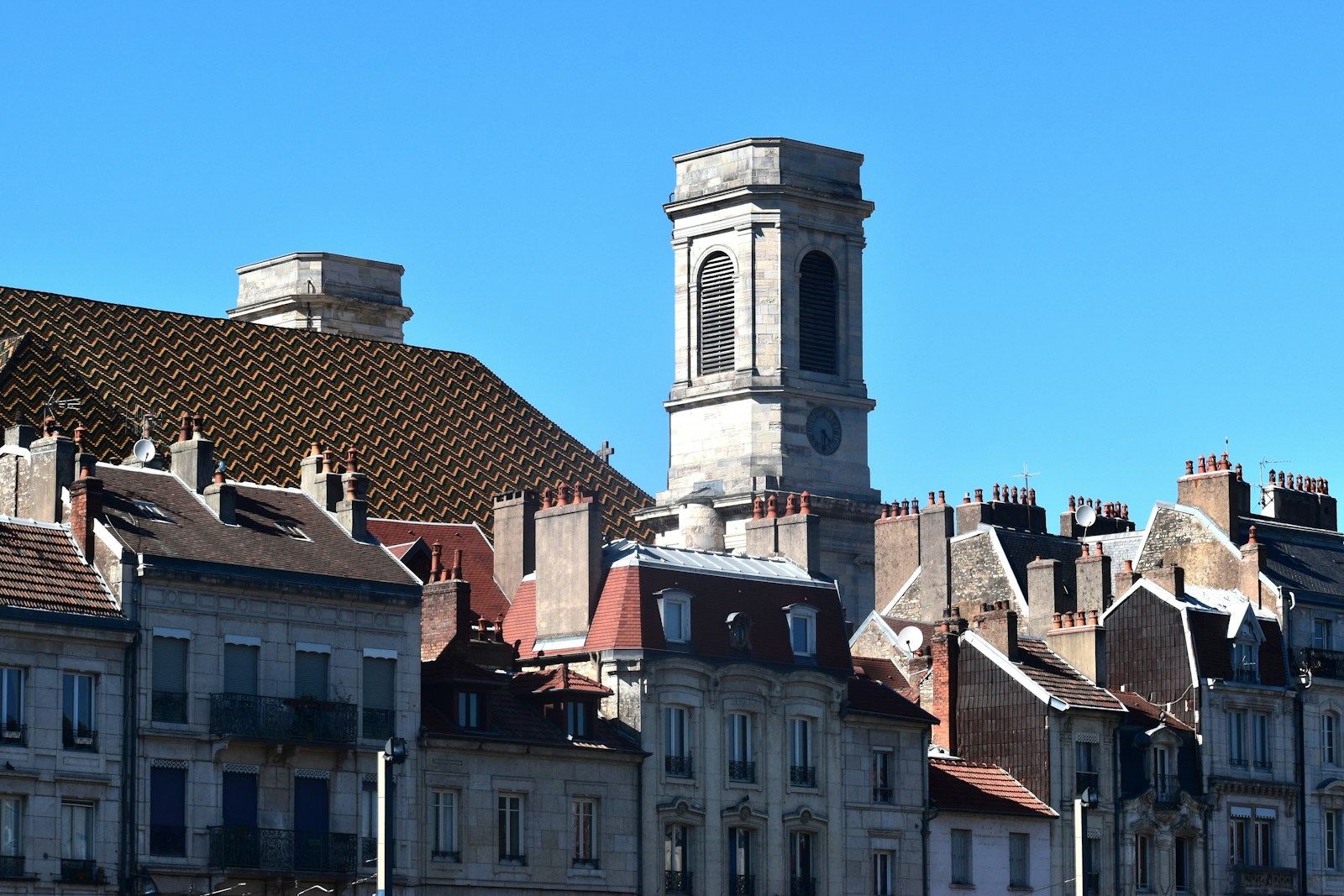 Historic buildings and church tower under blue sky