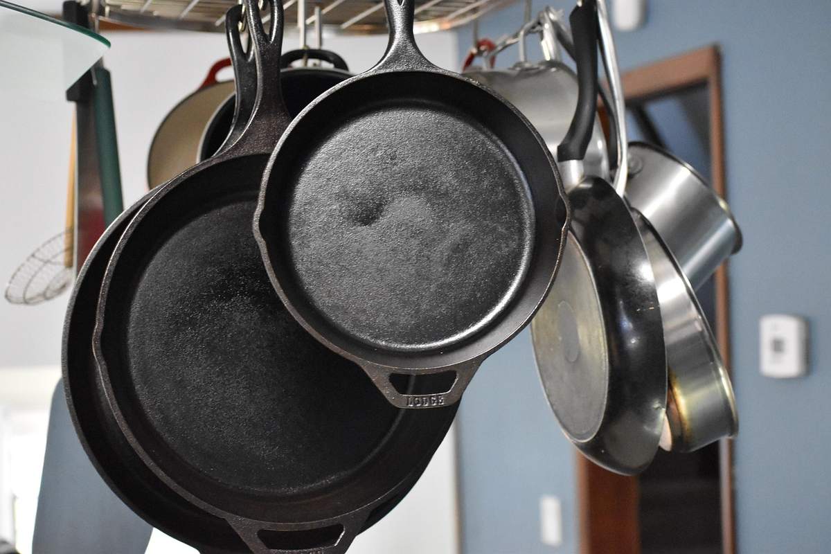 Casseroles en fonte et acier accrochées à un crochet dans une cuisine