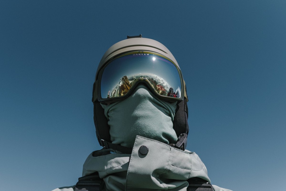 Person en casque, lunettes, masque et veste, regard vers le ciel