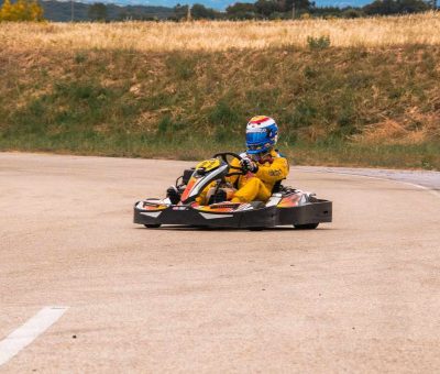 Un pilote en kart jaune conduit sur un circuit de terre