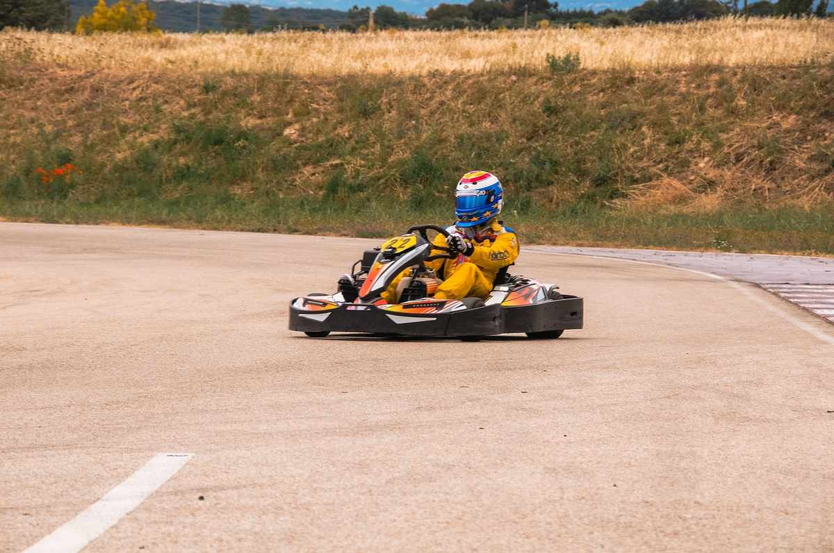 Un pilote en kart jaune conduit sur un circuit de terre