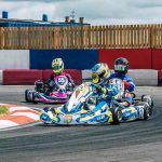 Trois karts dérapent en virage sur circuit, pilotes en casques colorés